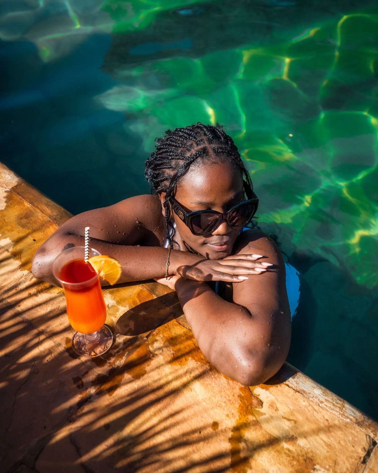 Guest resting on the pool edge with a drink